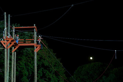 Harnessed person about to jump of orange ledge with small moon in the background