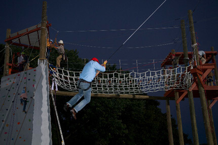 Person with blue shirt swinging from rope at night